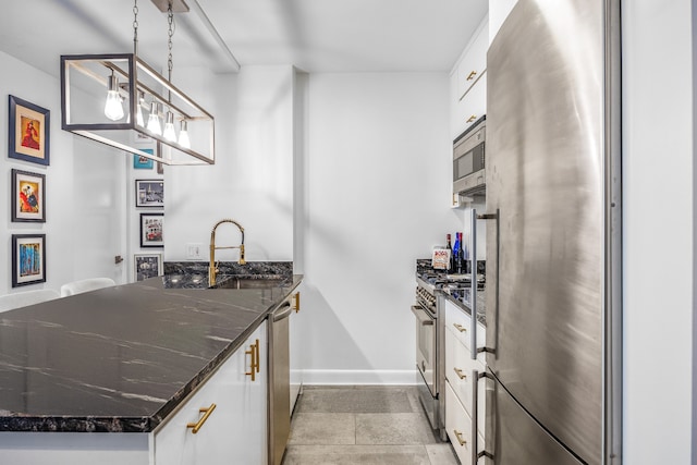 kitchen featuring sink, hanging light fixtures, dark stone counters, white cabinets, and appliances with stainless steel finishes