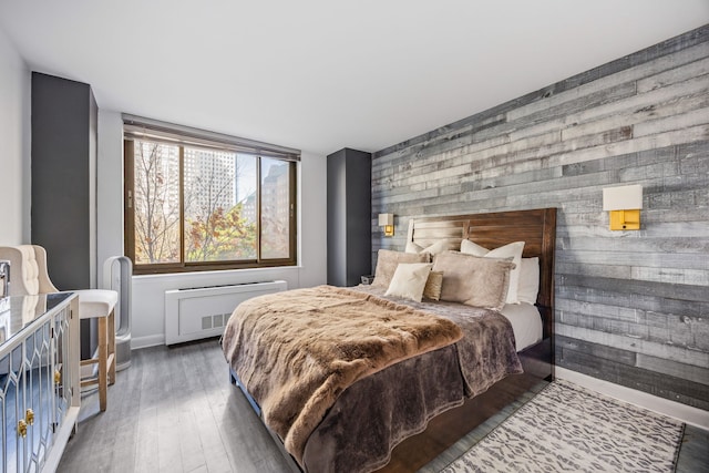 bedroom with wood walls, dark wood-type flooring, and radiator