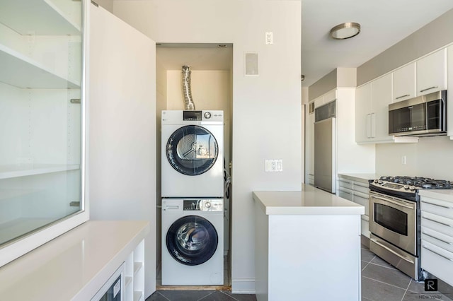 laundry area featuring dark tile patterned floors and stacked washing maching and dryer