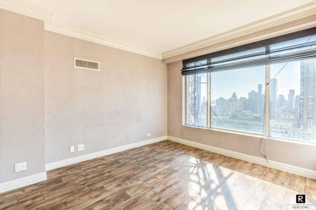 spare room featuring wood-type flooring and crown molding