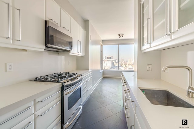 kitchen with white cabinets, stainless steel appliances, dark tile patterned floors, and sink