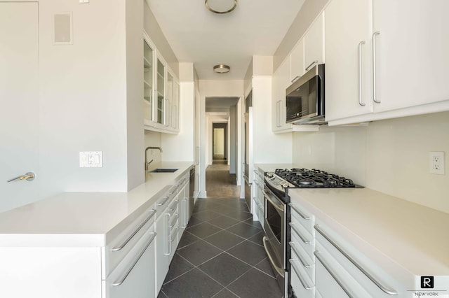 kitchen featuring dark tile patterned floors, sink, white cabinets, and stainless steel appliances