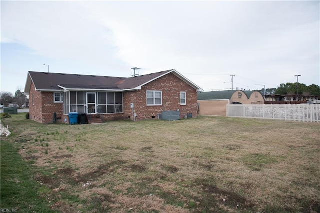 rear view of house with a lawn, central AC unit, and a sunroom