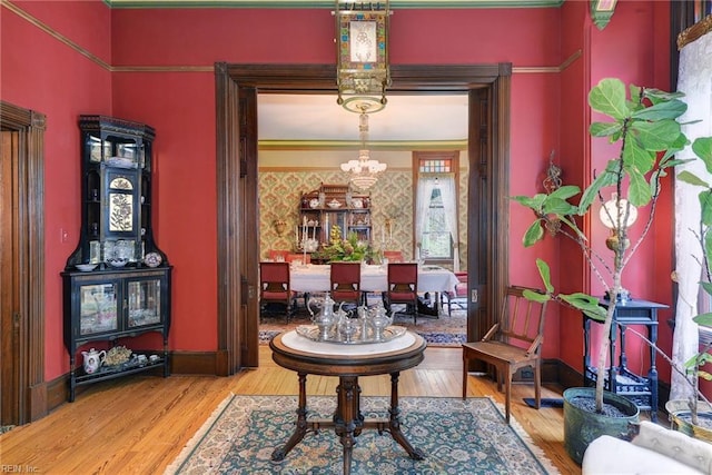 sitting room featuring an inviting chandelier, crown molding, light wood-type flooring, and a towering ceiling