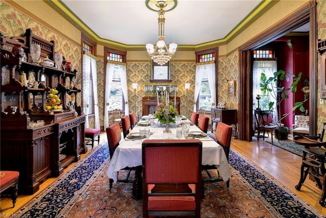 dining room with an inviting chandelier, crown molding, and light hardwood / wood-style flooring