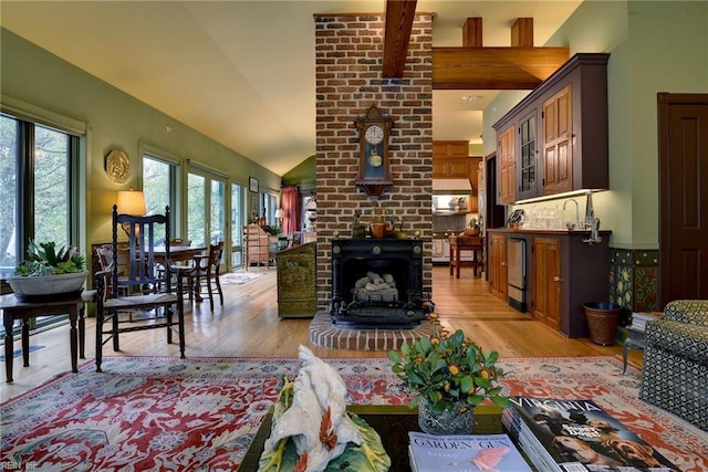 living room with a fireplace, lofted ceiling, brick wall, and light hardwood / wood-style flooring