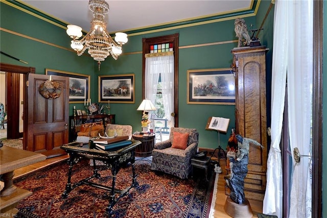 sitting room with crown molding, an inviting chandelier, and hardwood / wood-style flooring