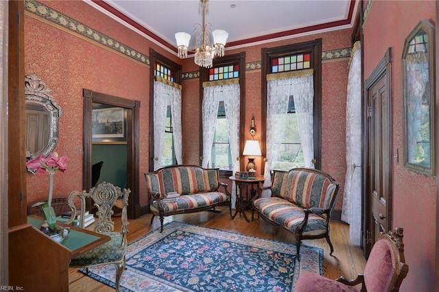 living area with ornamental molding, a chandelier, and hardwood / wood-style flooring