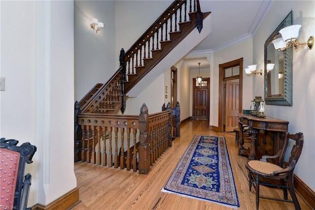 foyer entrance with ornamental molding, a notable chandelier, and light hardwood / wood-style flooring