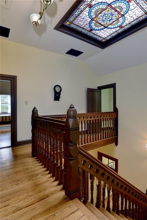 stairway with vaulted ceiling, light wood-type flooring, and an inviting chandelier