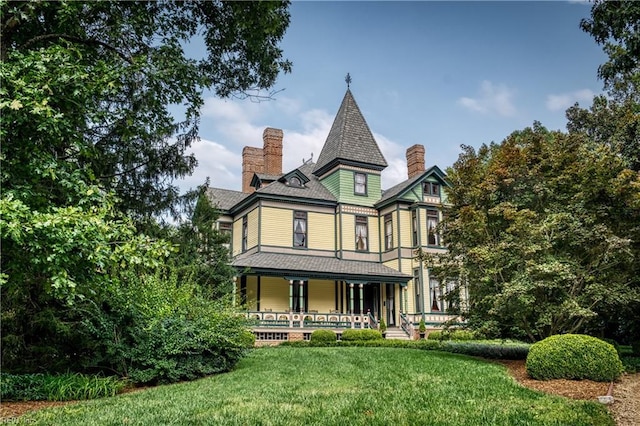 rear view of property featuring covered porch and a yard