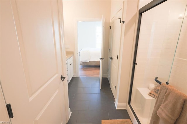 bathroom featuring a shower with shower door, vanity, and tile patterned floors