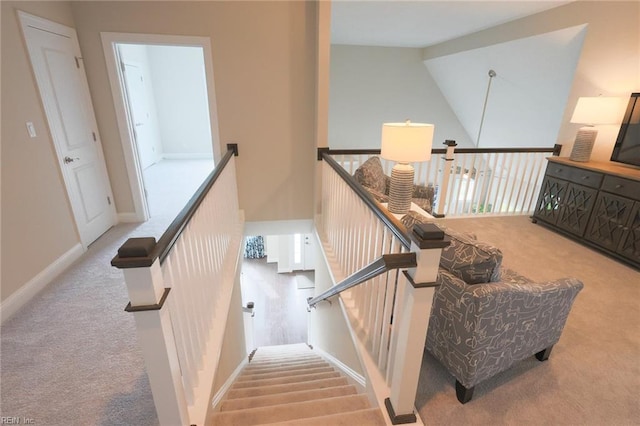 stairway featuring high vaulted ceiling and light colored carpet