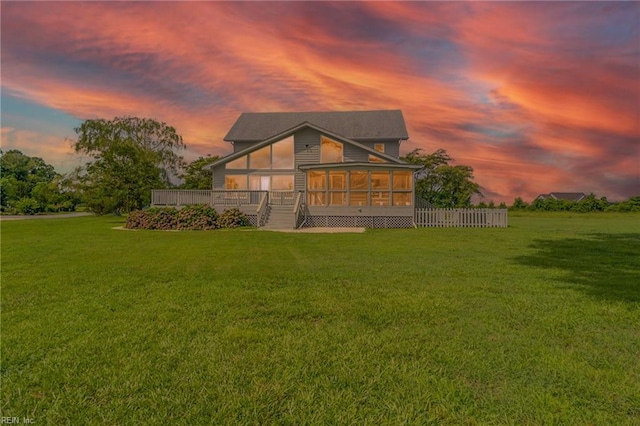 view of front facade featuring a wooden deck, a sunroom, and a lawn