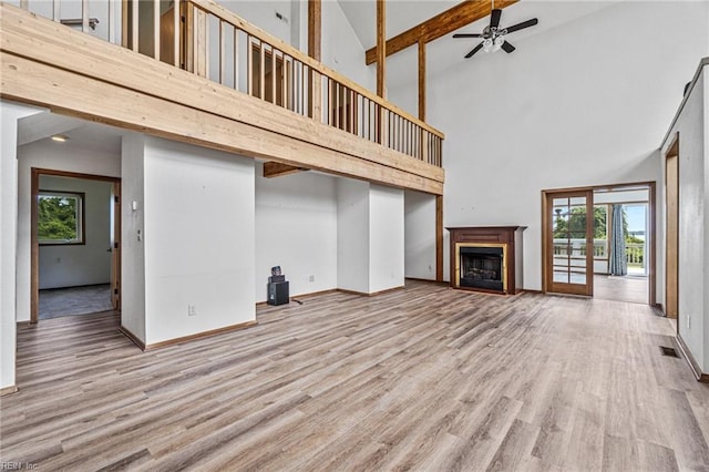 unfurnished living room with light hardwood / wood-style flooring, ceiling fan, and high vaulted ceiling