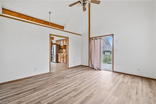 empty room with a high ceiling, ceiling fan, and light wood-type flooring