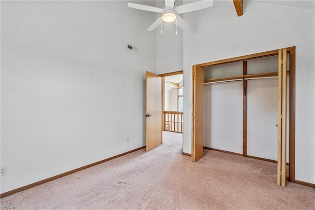 unfurnished bedroom featuring high vaulted ceiling, light colored carpet, and ceiling fan