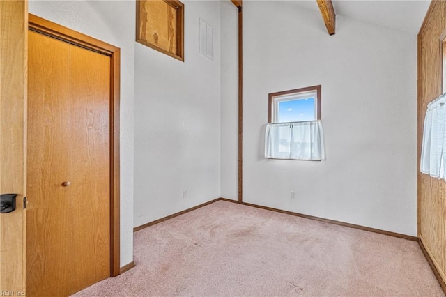 unfurnished bedroom featuring beam ceiling, light carpet, and a closet