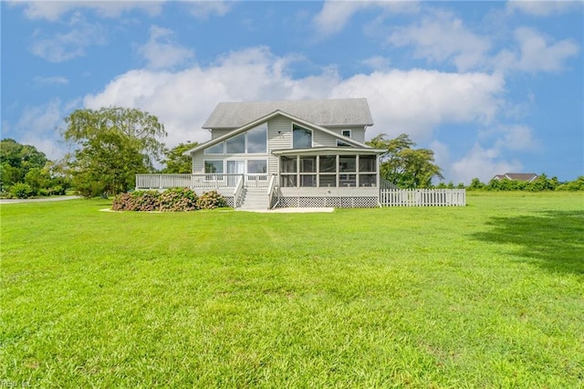 back of property featuring a wooden deck, a yard, and a sunroom