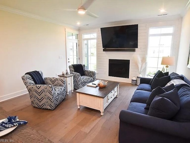 living room with a fireplace, ceiling fan, ornamental molding, and dark wood-type flooring