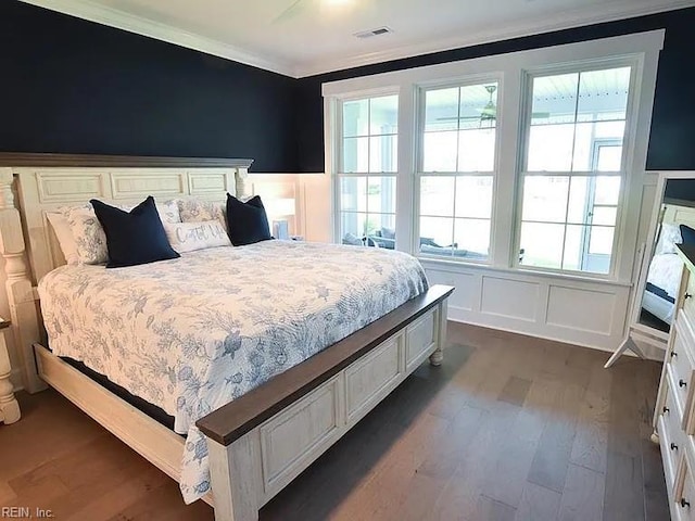 bedroom featuring dark hardwood / wood-style floors, multiple windows, and ornamental molding