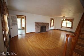 364 Millers Ln, Susan, VA 23163 - unfurnished living room with a notable chandelier, plenty of natural light, a fireplace with raised hearth, and wood finished floors