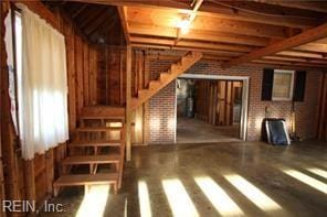 364 Millers Ln, Susan, VA 23163 - unfurnished living room with stairs, brick wall, and wood finished floors