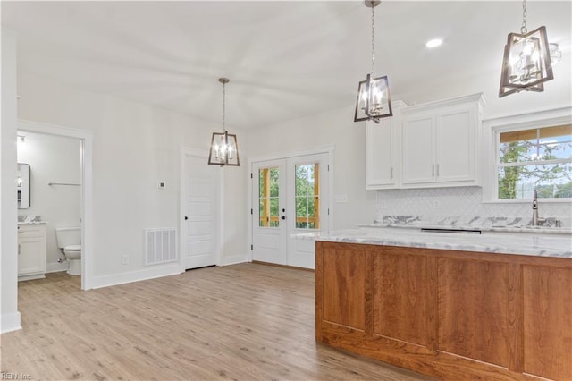 kitchen featuring sink, light stone countertops, and white cabinetry