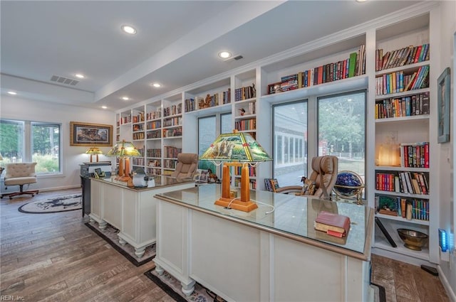 office space with built in shelves, a tray ceiling, and wood-type flooring