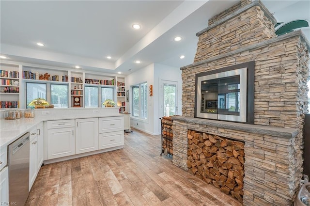 kitchen featuring dishwasher, white cabinetry, light hardwood / wood-style floors, and a raised ceiling