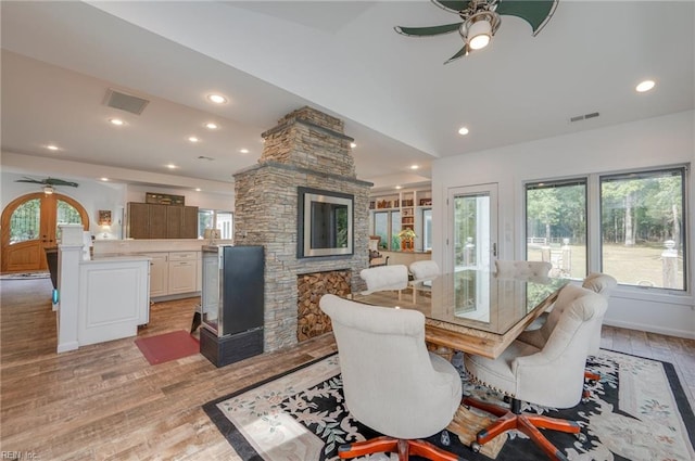 dining space with ceiling fan, light wood-type flooring, and a fireplace