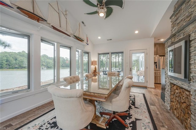 sunroom with lofted ceiling, ceiling fan, a healthy amount of sunlight, and a water view