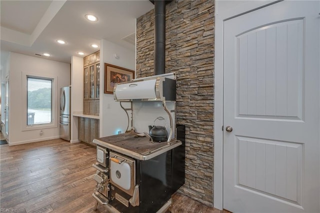 kitchen featuring a wood stove, dark hardwood / wood-style floors, and stainless steel refrigerator