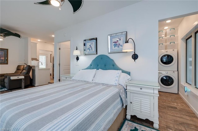 bedroom featuring hardwood / wood-style floors, ceiling fan, and stacked washer and dryer