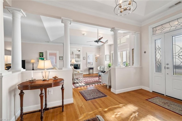 foyer featuring light hardwood / wood-style flooring, decorative columns, ornamental molding, and ceiling fan with notable chandelier