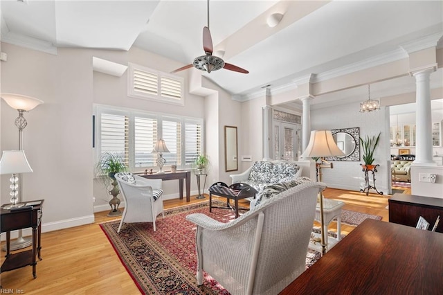 living room with crown molding, light hardwood / wood-style floors, ceiling fan with notable chandelier, and ornate columns