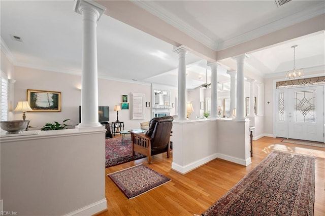 foyer with decorative columns, light wood-type flooring, and a healthy amount of sunlight