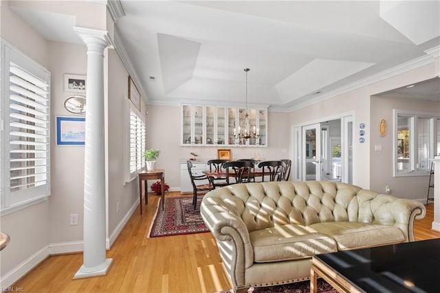 living room featuring light hardwood / wood-style floors, decorative columns, and a tray ceiling