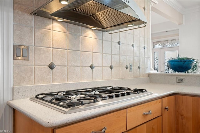 kitchen with premium range hood, stainless steel gas stovetop, tasteful backsplash, and crown molding