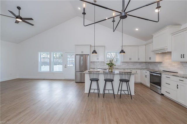 kitchen with appliances with stainless steel finishes, a kitchen bar, a kitchen island, and white cabinets