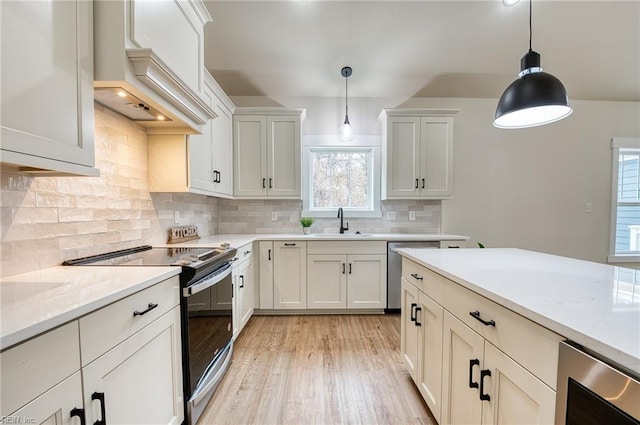 kitchen with hanging light fixtures, light stone countertops, appliances with stainless steel finishes, and sink