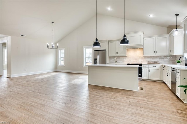 kitchen with white cabinetry, a center island, hanging light fixtures, appliances with stainless steel finishes, and light hardwood / wood-style floors