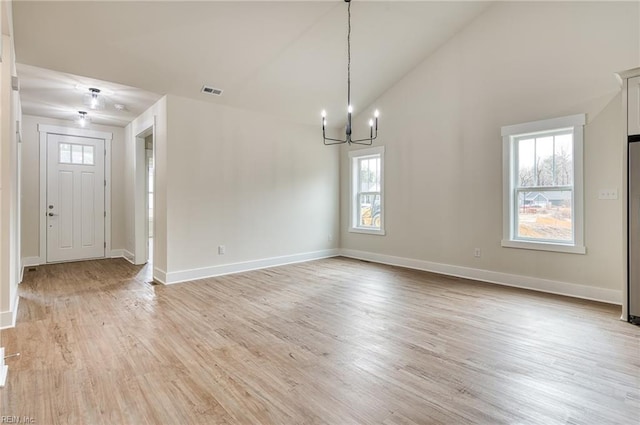 foyer entrance with high vaulted ceiling, light hardwood / wood-style floors, and a notable chandelier