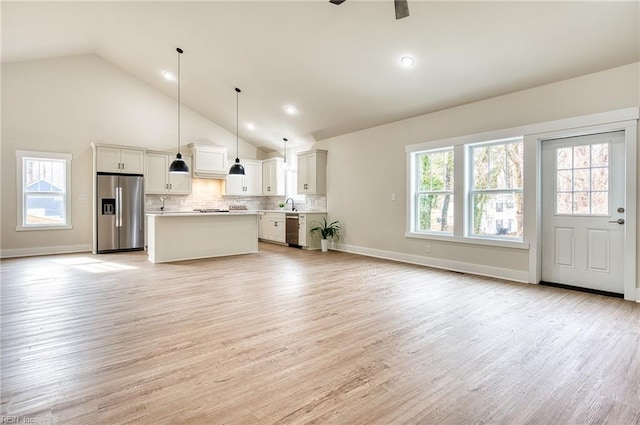 kitchen with white cabinetry, decorative light fixtures, a center island, appliances with stainless steel finishes, and plenty of natural light