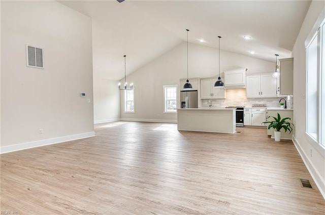 kitchen featuring a kitchen island, decorative light fixtures, white cabinetry, light hardwood / wood-style floors, and stainless steel appliances