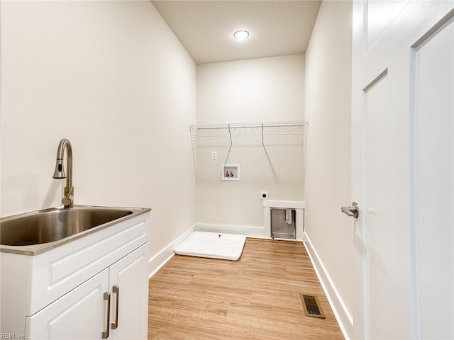 clothes washing area with sink, cabinets, washer hookup, hookup for an electric dryer, and light wood-type flooring