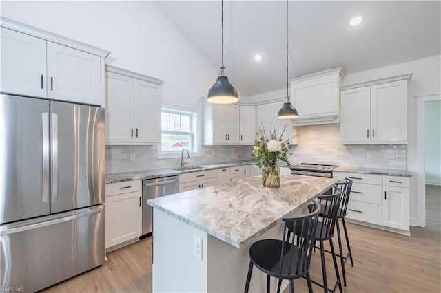 kitchen featuring pendant lighting, sink, appliances with stainless steel finishes, white cabinetry, and a center island