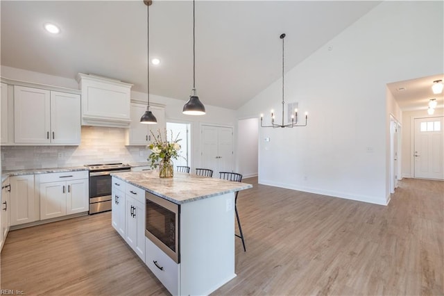 kitchen featuring electric stove, built in microwave, pendant lighting, and white cabinetry