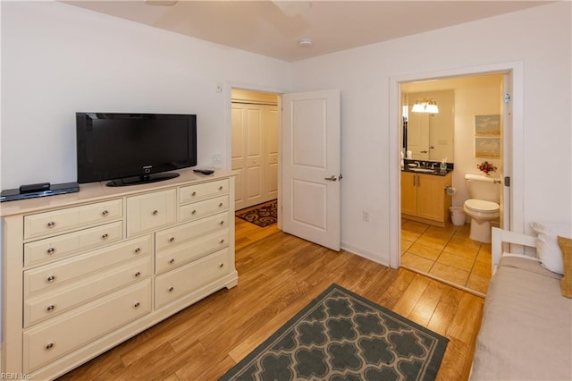 bedroom with ensuite bath, light hardwood / wood-style floors, and a closet