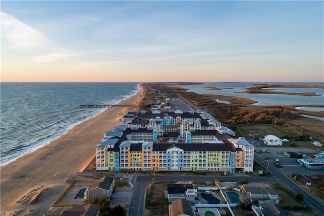 aerial view at dusk featuring a beach view and a water view